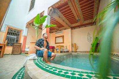 a man sitting on the edge of a swimming pool at Riad Euphorbe in Marrakech