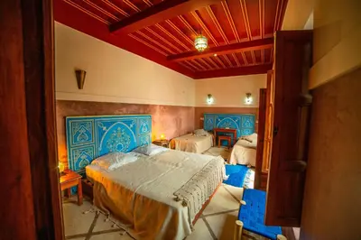 a bedroom with a large bed with blue accents at Riad Euphorbe in Marrakech