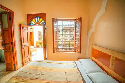 a bedroom with a bed and a window and a door at Riad Euphorbe in Marrakech
