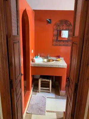 a bathroom with a sink and an orange wall at Riad Euphorbe in Marrakech