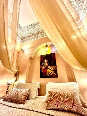 a bedroom with a bed with curtains and a painting at Riad Fatinat Marrakech in Marrakech