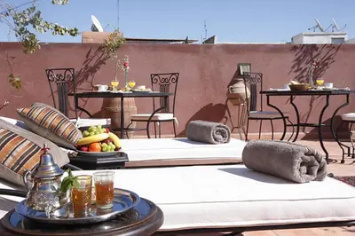 two beds on a patio with tables and chairs at Riad Shaloma in Marrakech