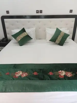 a bed with green and white pillows on it at Hotel Al Kabir in Marrakech