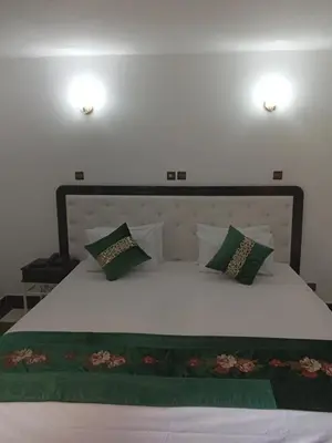 a bedroom with a white bed with green pillows at Hotel Al Kabir in Marrakech
