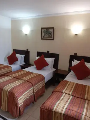 a hotel room with three beds with red pillows at Hotel Al Kabir in Marrakech
