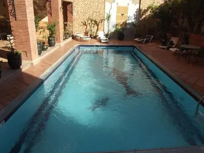 a swimming pool with blue water in a yard at Hotel Al Kabir in Marrakech