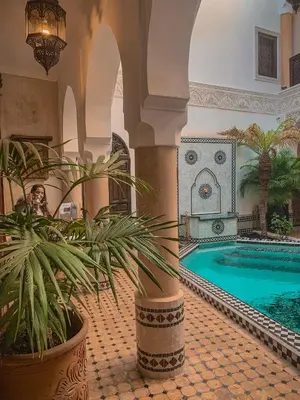 a person sitting in a room with a pool in a building at Riad Abaka hotel & boutique in Marrakech