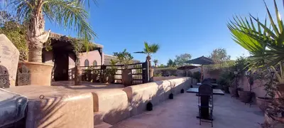 a house with a fence and palm trees on a sidewalk at Dar Darma in Marrakech