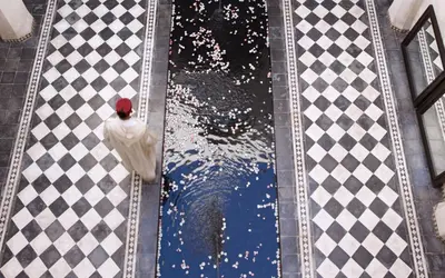 an overhead view of a pool with a chicken on a checkered floor at Dar Darma in Marrakech