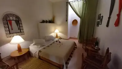 a bedroom with a bed and a table and a window at Dar El Kharaz in Marrakech