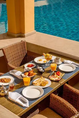 a table with plates of food on it next to a pool at Grand Plaza Marrakech in Marrakech