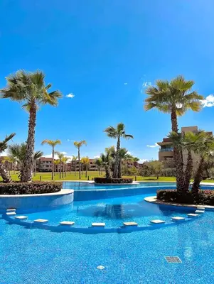 a swimming pool with palm trees in a resort at Marrakech golf city prestigia in Marrakech