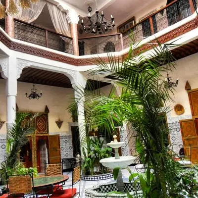 a large room with a fountain and plants in it at Riad Chennaoui in Marrakech