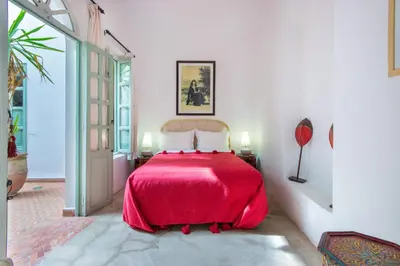 a bedroom with a bed with a red bedspread at Riad Helen in Marrakech