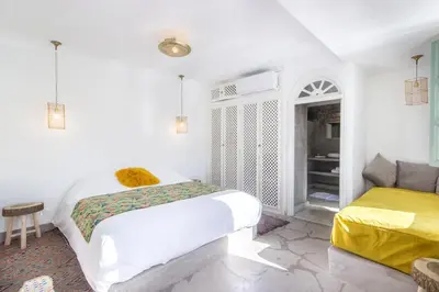 a white bedroom with two beds and a window at Riad Helen in Marrakech
