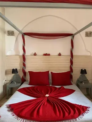 a red and white bed with a red blanket on it at Riad Karmanda in Marrakech