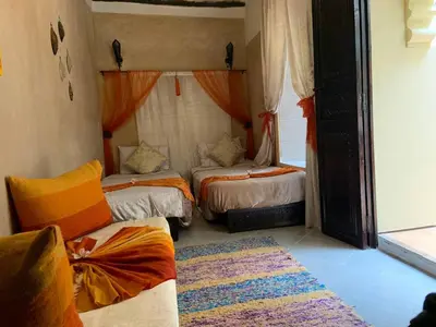 a bedroom with two beds and a rug at Riad Karmanda in Marrakech