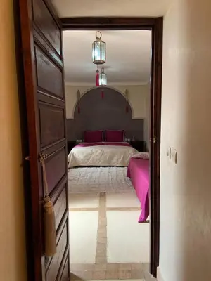 a bedroom with a bed with pink sheets and a mirror at Riad Karmanda in Marrakech