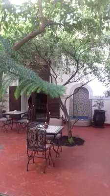 a patio with tables and chairs under a tree at Riad Sidi Ayoub in Marrakech