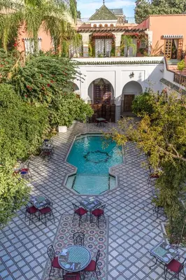 a courtyard with a pool with chairs and a table at Palais Dar Donab in Marrakech