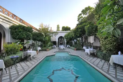 a swimming pool in a courtyard with tables and chairs at Palais Dar Donab in Marrakech