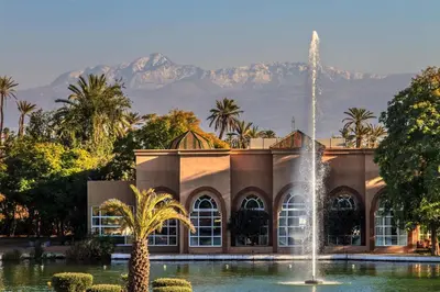 a fountain in front of a building with mountains in the background at Barceló Palmeraie Oasis Resort in Marrakech