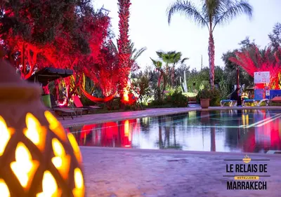 a swimming pool with red lights and palm trees at Le Relais De Marrakech in Marrakech