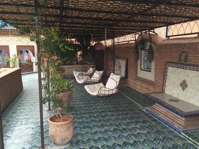 an outdoor patio with chairs and plants in a building at Riad Palais Sebban in Marrakech