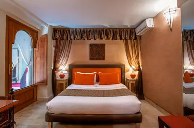 a bedroom with a large bed with orange pillows at Riad l'Heure d'Eté in Marrakech
