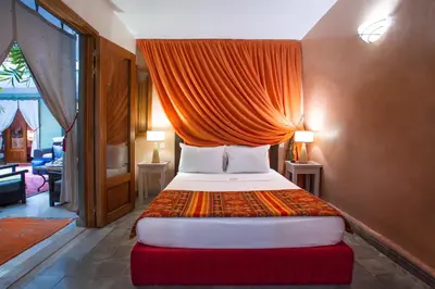 a bedroom with a large bed with an orange canopy at Riad l'Heure d'Eté in Marrakech