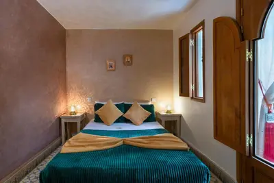 a bedroom with a bed with green sheets and pillows at Riad l'Heure d'Eté in Marrakech