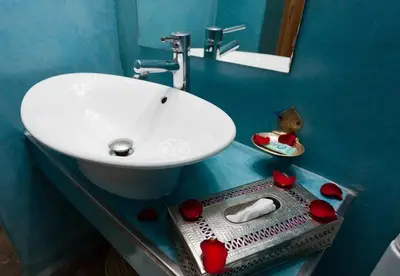 a bathroom with a sink and a mirror and red roses at Riad l'Heure d'Eté in Marrakech