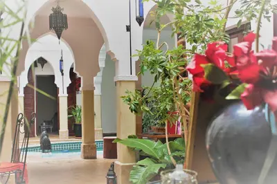 a vase filled with red flowers next to a building at Les Jardins Mandaline in Marrakech