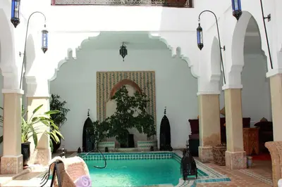 a swimming pool in a building with a fountain at Les Jardins Mandaline in Marrakech
