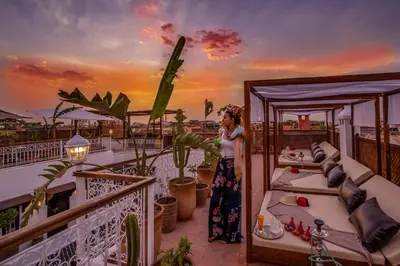 a woman standing on a balcony with two beds at Riad Safran et Cannelle & Spa in Marrakech