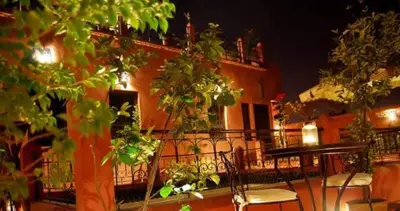 a balcony with chairs and a building at night at Riad D'Airain in Marrakech