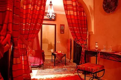 a living room with red curtains and a table at Riad D'Airain in Marrakech