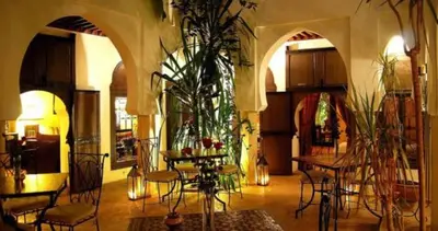 a living room with tables and chairs and plants at Riad D'Airain in Marrakech