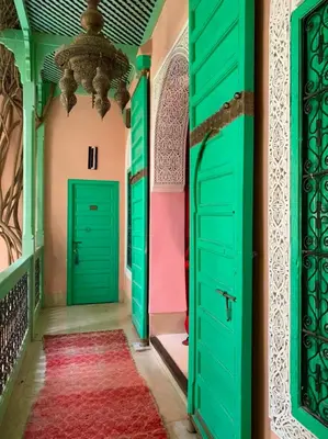 a hallway with green doors and a red rug at The Bohemian Jungle in Marrakech