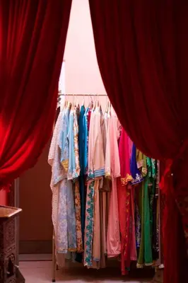 a rack of clothes in a store with red curtains at The Bohemian Jungle in Marrakech