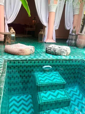 a swimming pool with a green tiled floor and pillows at The Bohemian Jungle in Marrakech
