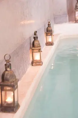 a group of lanterns on a wall next to a swimming pool at Riad Chayma Marrakech in Marrakech