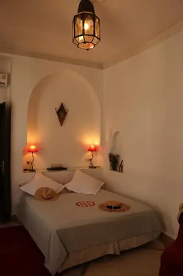 a bedroom with a bed with two lamps on it at Riad Chergui in Marrakech