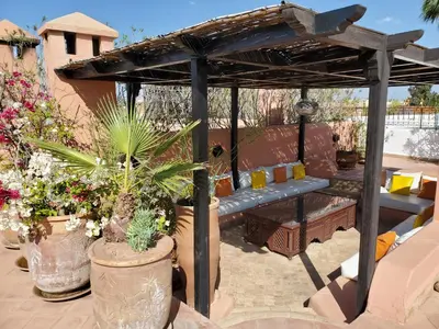 a wooden pergola with a bench and some plants at Riad Chergui in Marrakech