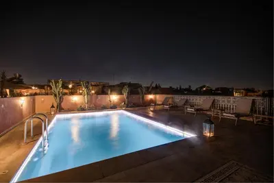 a swimming pool at night with lights on a roof at Riad Les Oliviers & Spa in Marrakech
