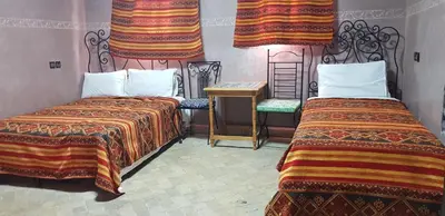 a room with two beds and a table and a chair at Hotel Wissam in Marrakech