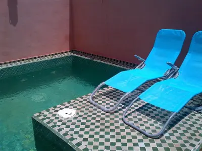 a swimming pool with two blue chairs in the water at Riad Lila in Marrakech