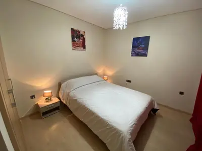 a bedroom with a white bed and two lamps at APPARTEMENT Golf Marrakech prestigia in Marrakech