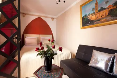 a bedroom with a bed and a couch and a vase with flowers at Riad Le Rubis in Marrakech