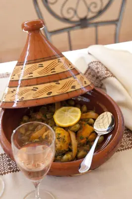 a wooden bowl filled with food and a glass of wine at Riad Le Rubis in Marrakech